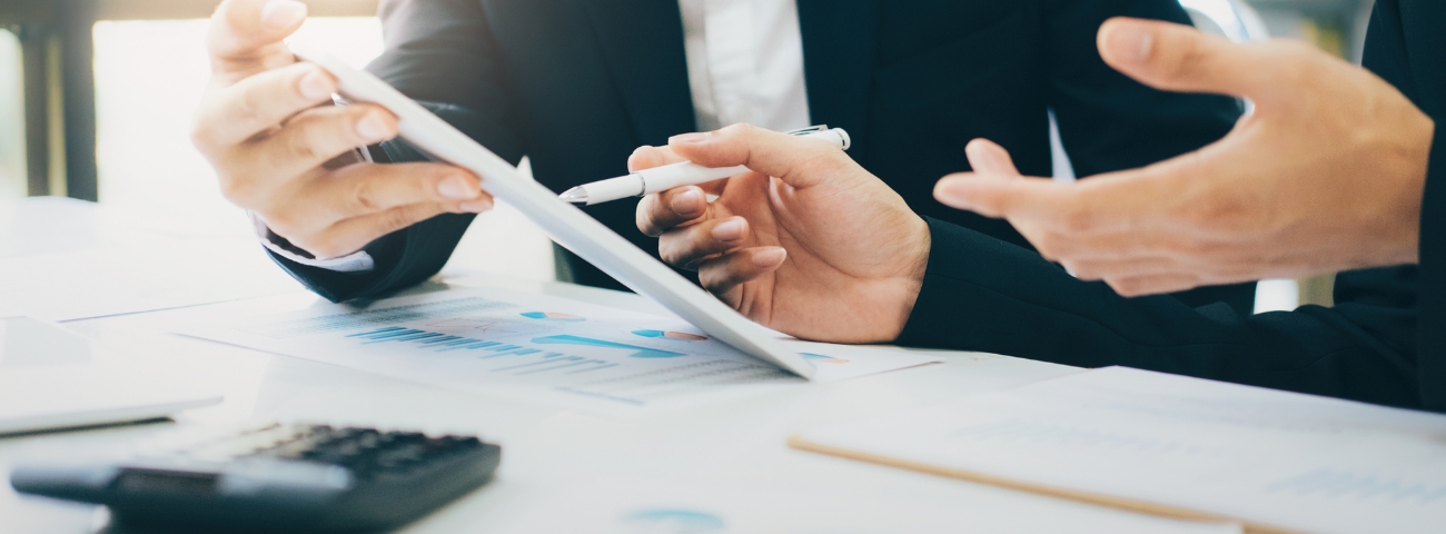 A CFO reviewing a finances and leases with a colleague in a office, surrounded by financial reports and audit documents—illustrating the theme of visibility and control over lease obligations.
